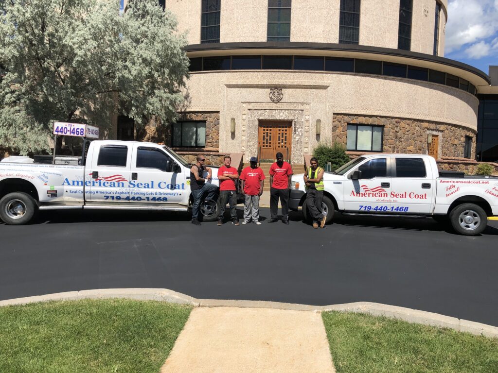 Professional sealcoating team with branded trucks and completed parking lot project