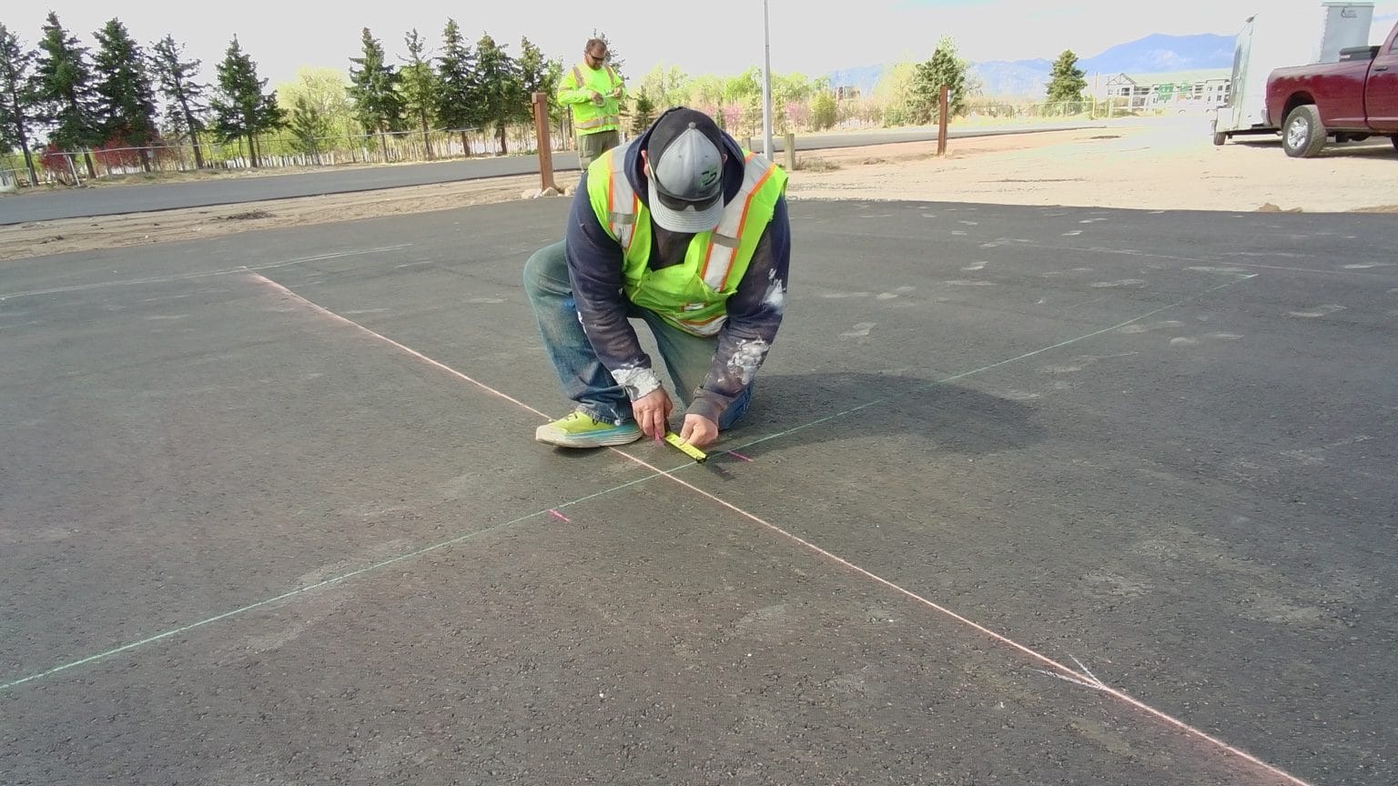Crew laying out yellow parking-lot striping on new asphalt